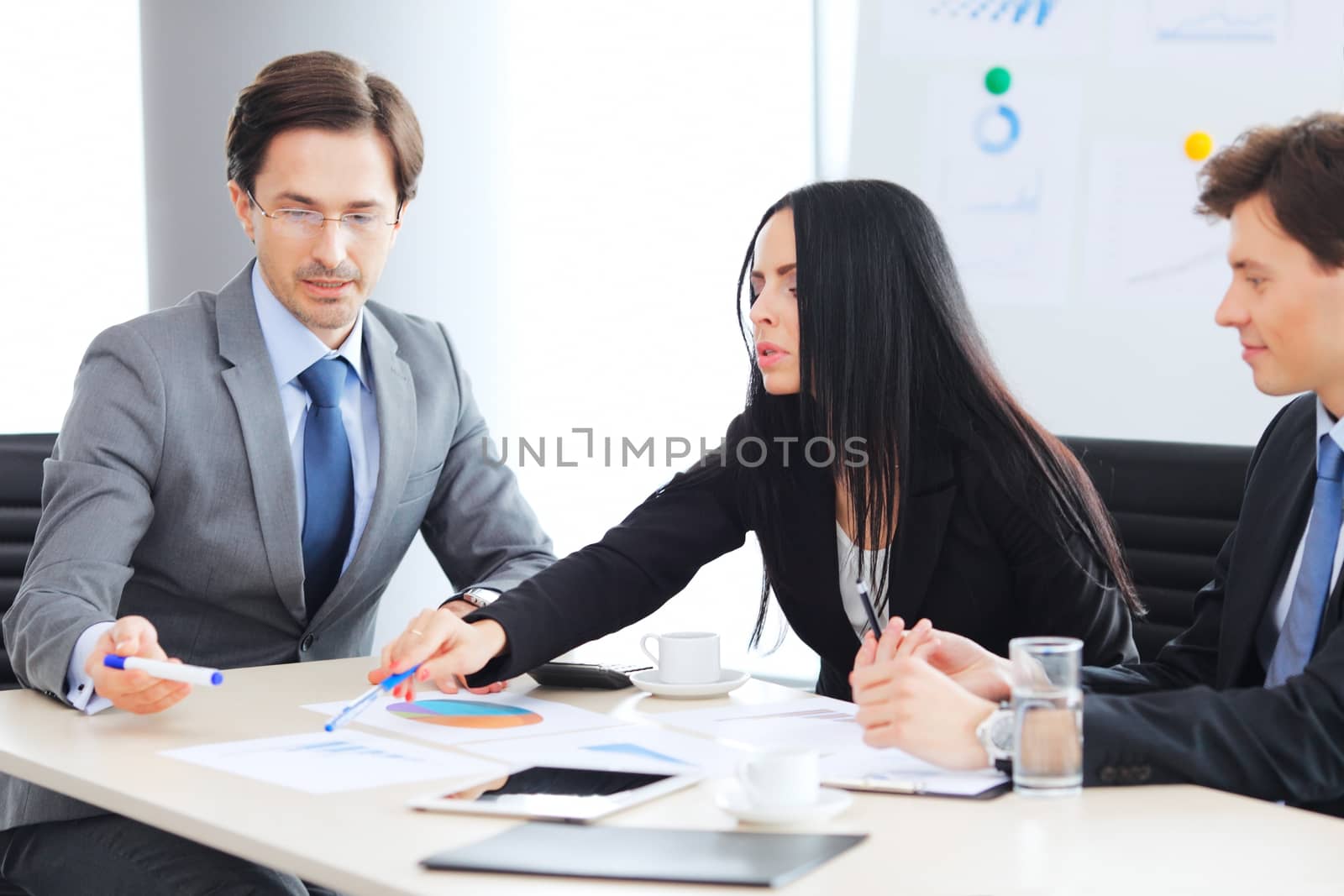 Workers at business meeting looking at presentation of financial reports in modern office