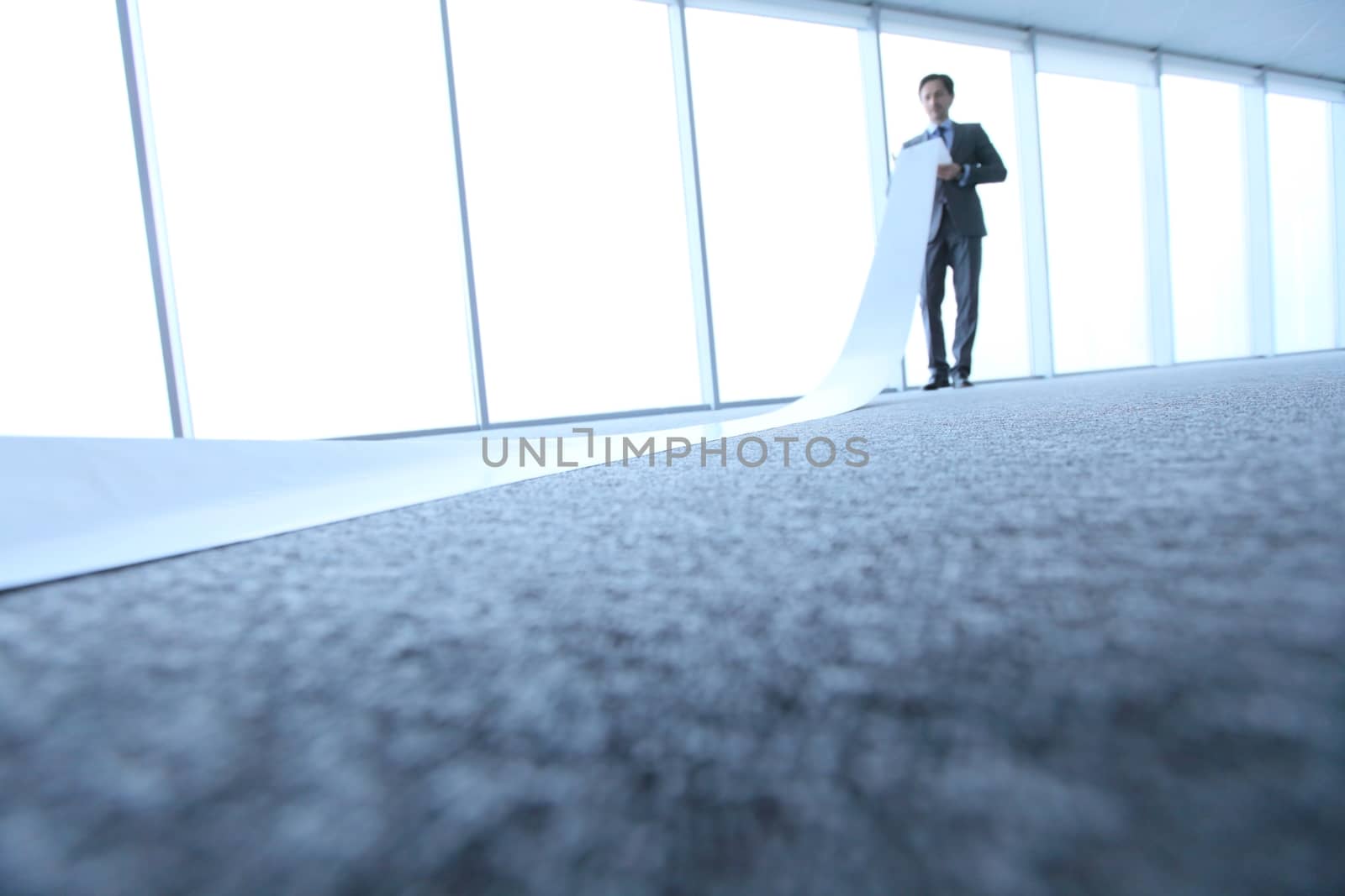 Office worker unrolling long sheet of paper