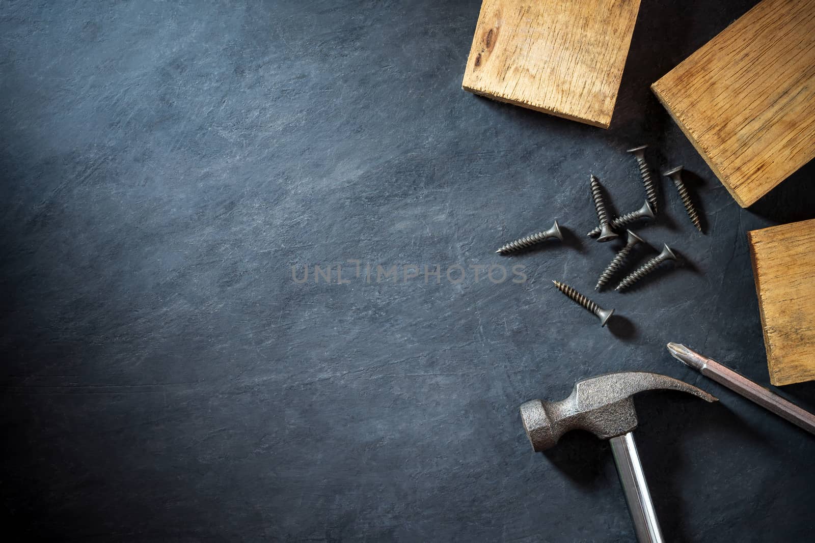 Hammer and lumber on black cement background. Top view and copy space for text. Concept of carpenter or construct.