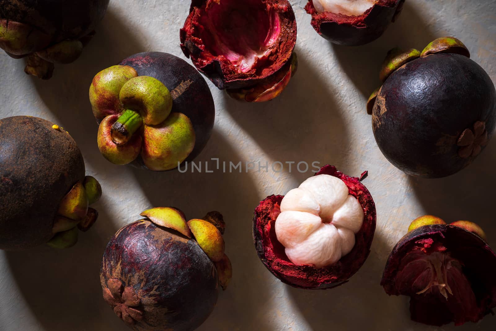 Mangosteen on cement floor and sunlight. Is a seasonal fruit in Thailand. Top view and closeup.