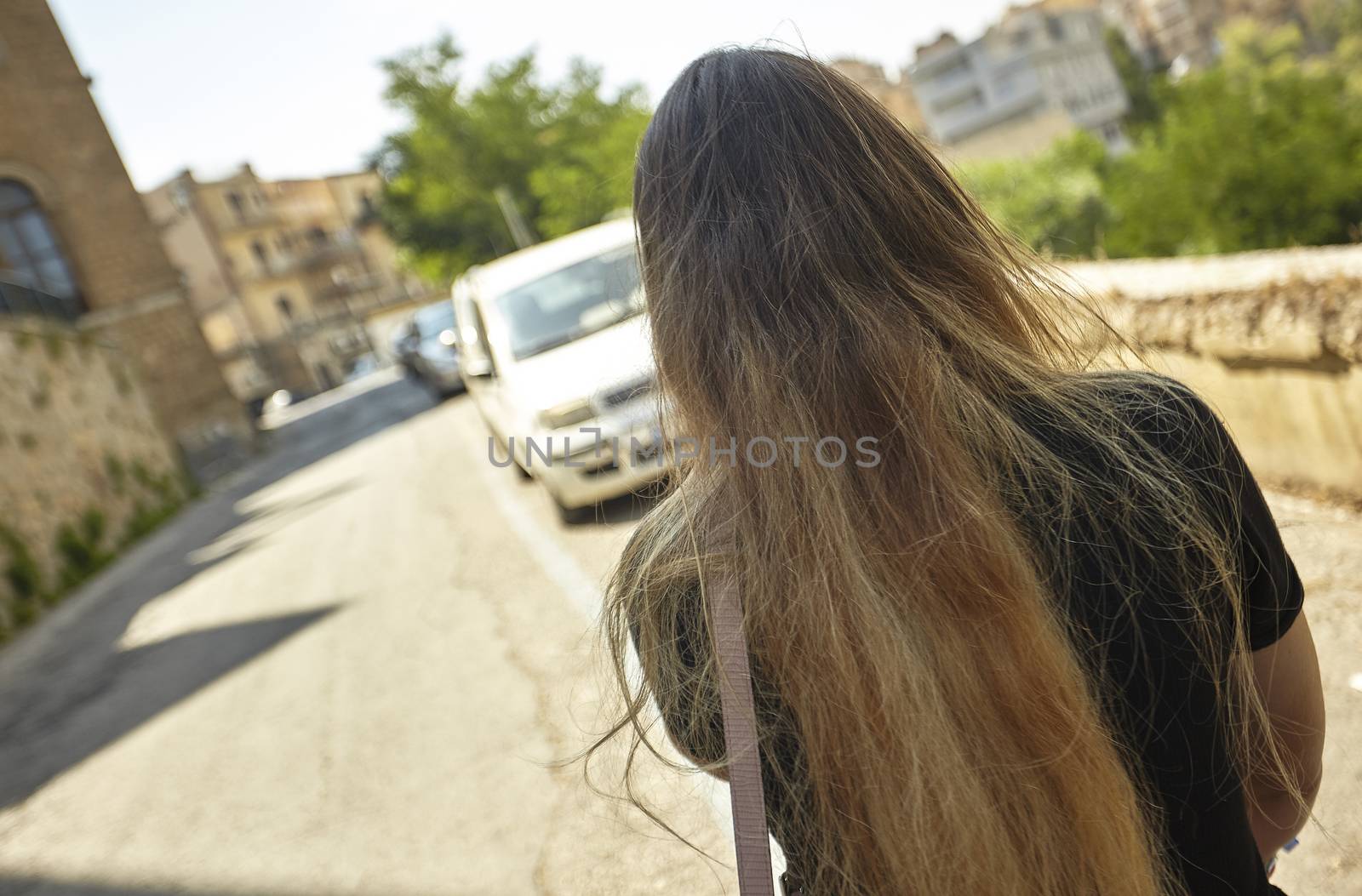 Girl from the back walks alone in the street during daytime