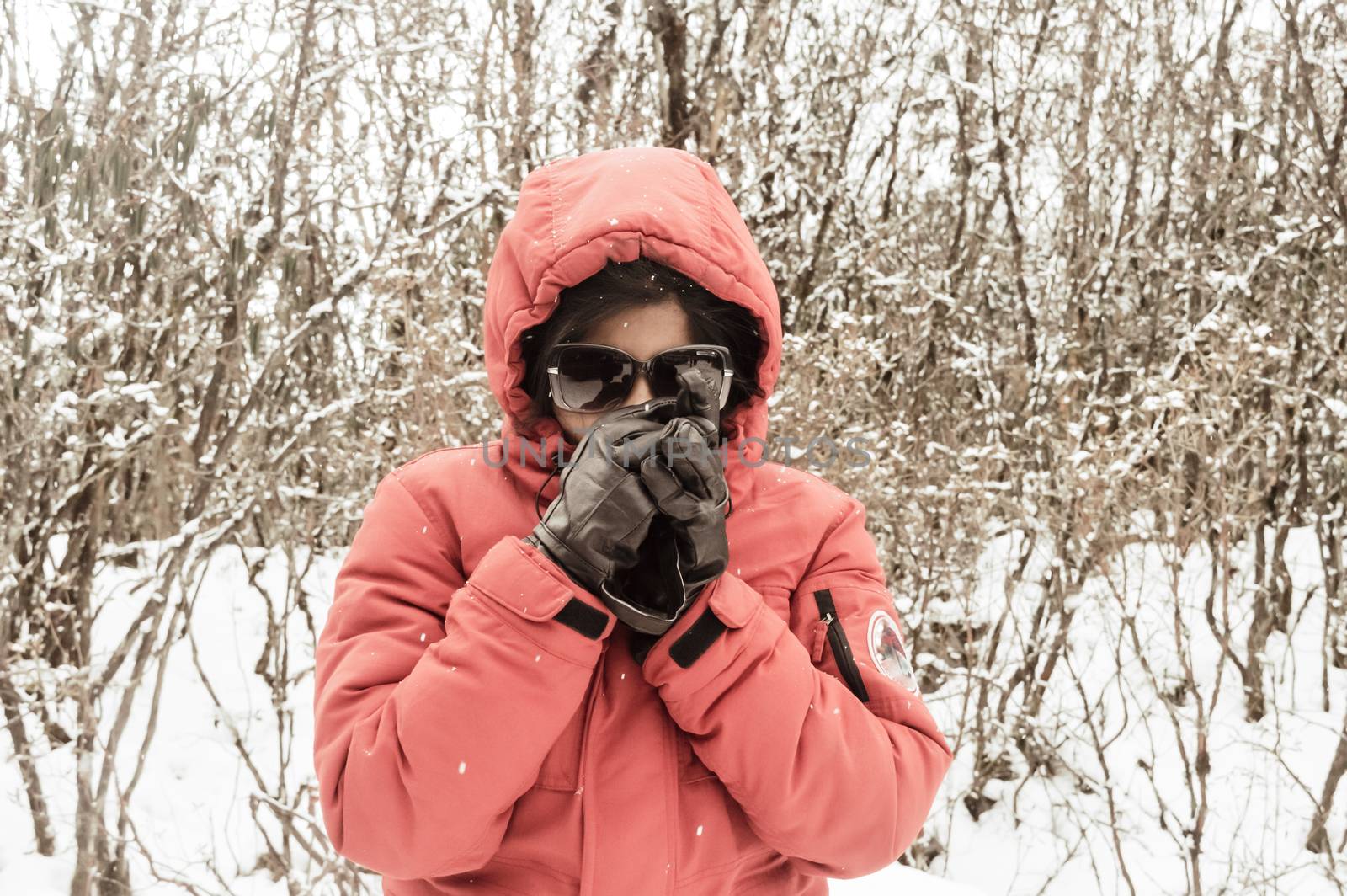 Smiling happy joyful Portrait of a Woman wearing a red pullover jacket and gloves enjoying first snow while shakes off snowball. Enjoy Snowing day view in winter. Rural village Jammu and Kashmir India