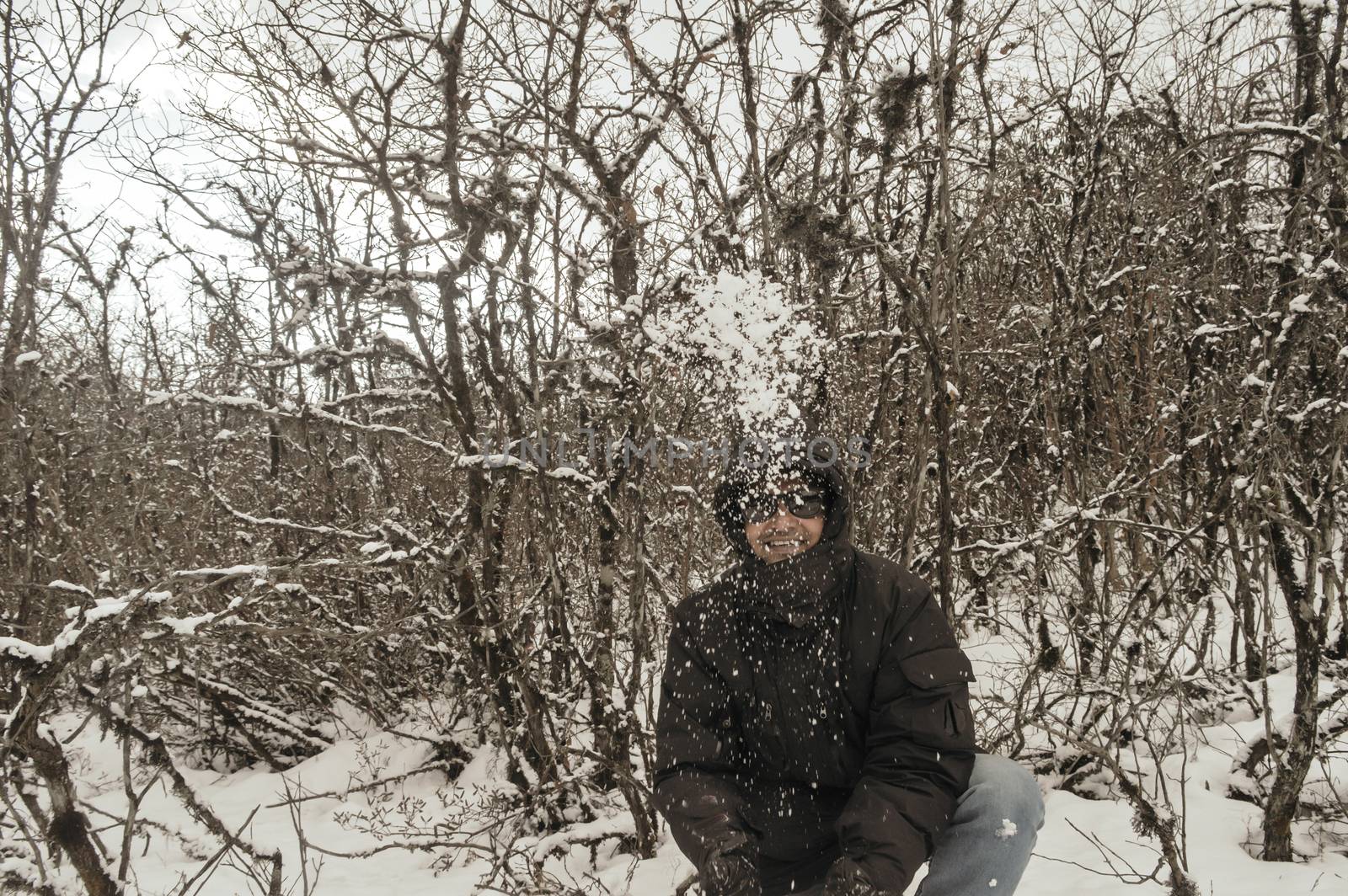 Smiling happy joyful Portrait of a Man wearing a black pullover jacket enjoying first snow playing and throwing snowball in air. Enjoy Snowing day view in winter. Rural village Jammu and Kashmir India by sudiptabhowmick