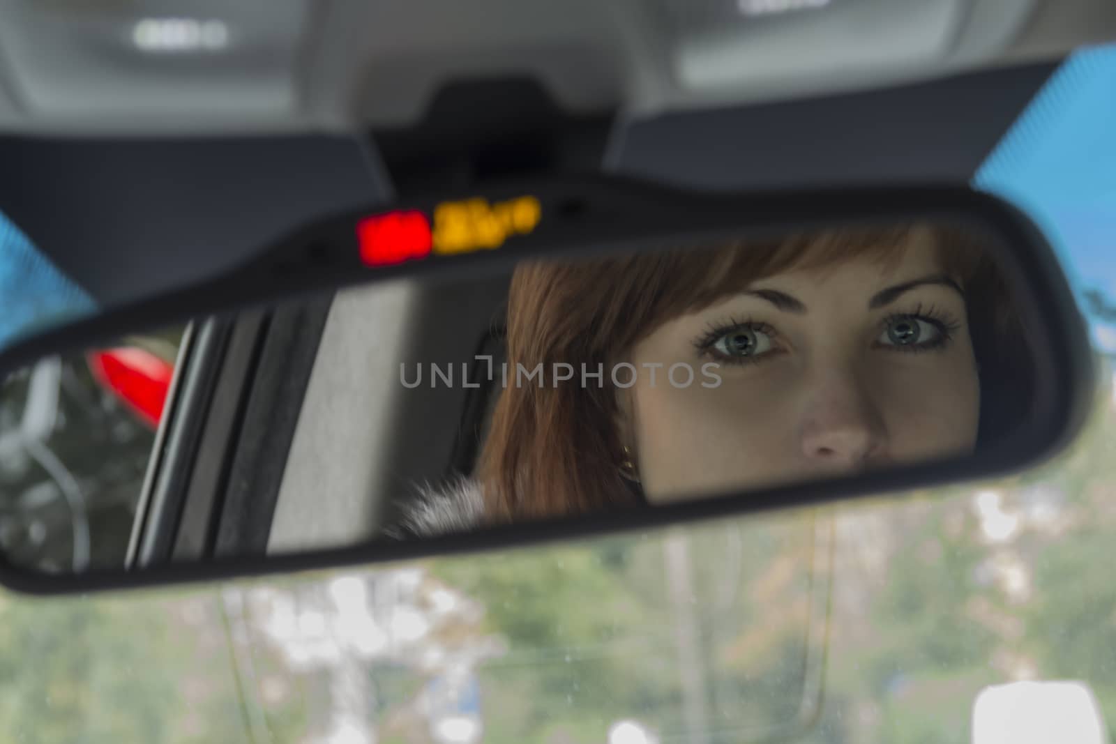 The eyes of a young girl looking in the rearview mirror of the vehicle