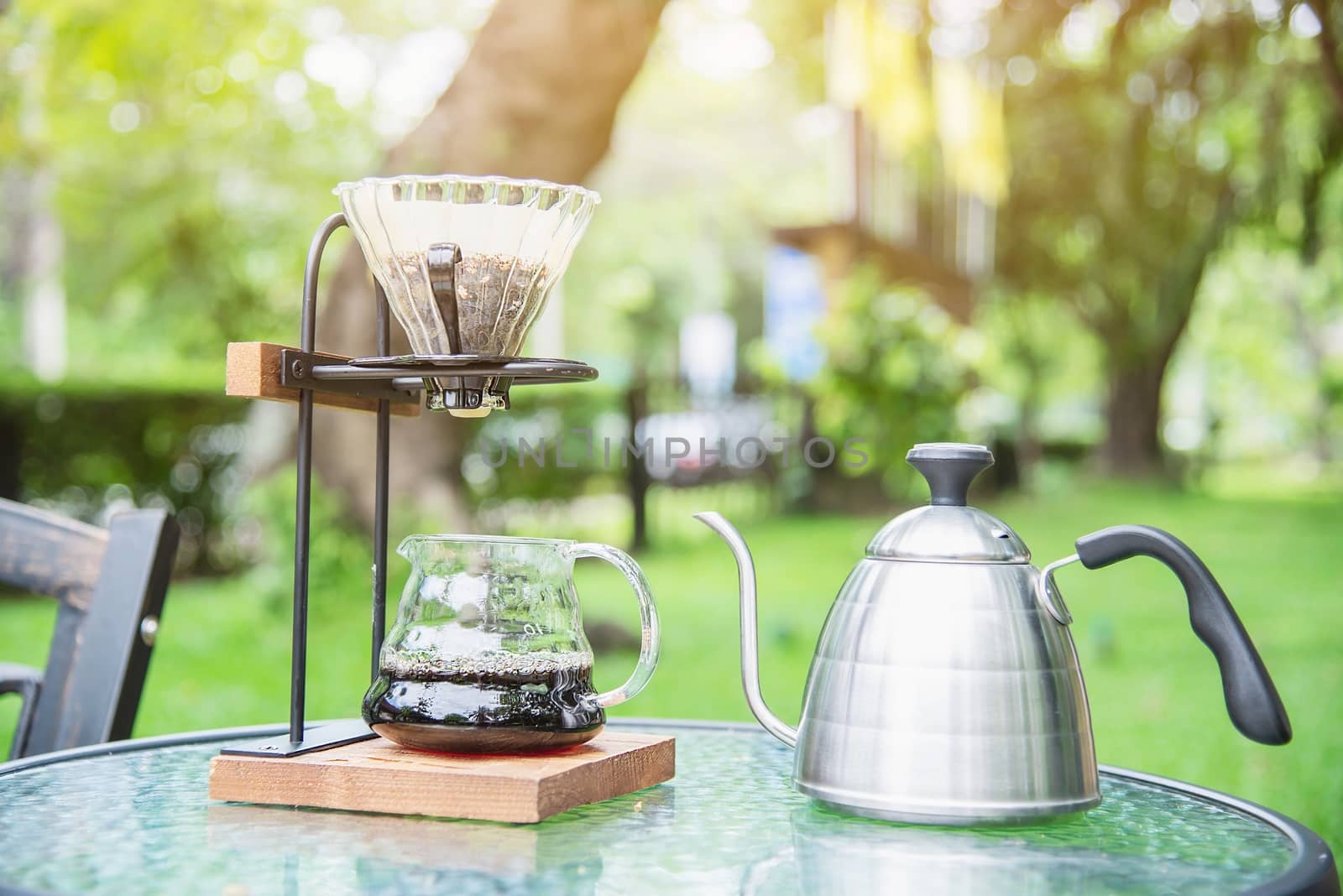 Making drip coffee in vintage coffee shop with green garden nature background - fresh coffee in nature concept