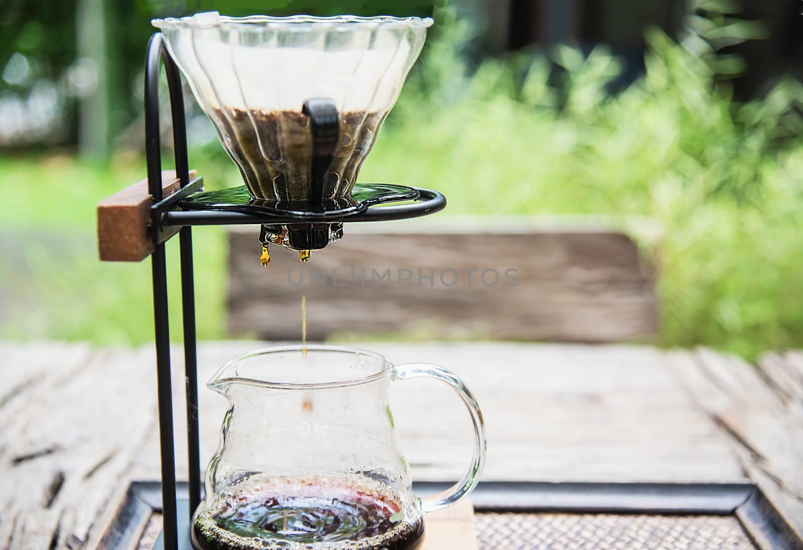 Making drip coffee in vintage coffee shop with green garden nature background - fresh coffee in nature concept