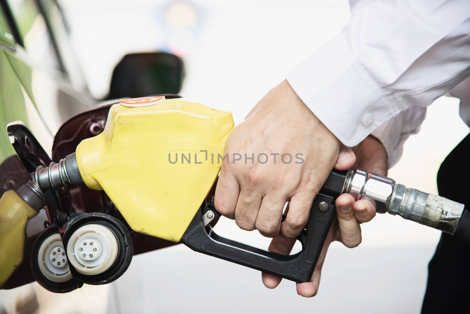Man putting gasoline fuel into his car in a pump gas station by pairhandmade