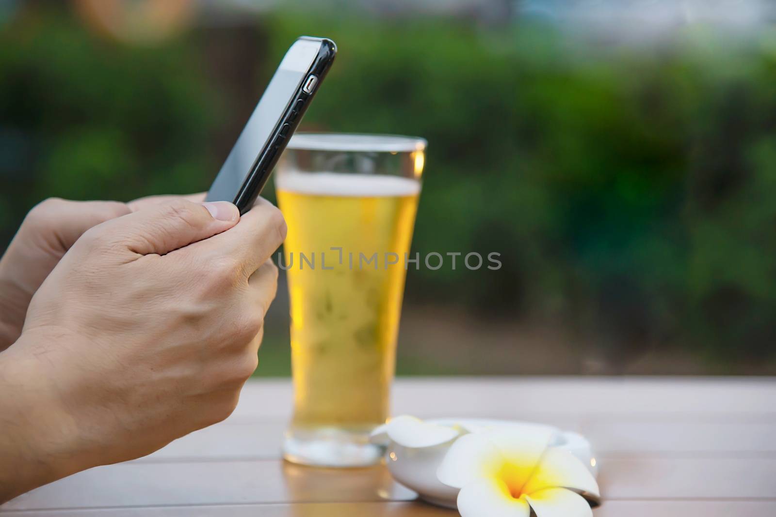 Man using mobile during happy time relax in restaurant with softdrink and green garden background - people relax with technology lifestyle concept