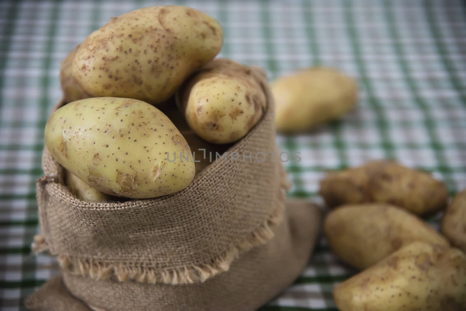 Fresh potato ready for cooking with potato sack background - potato cooking concept