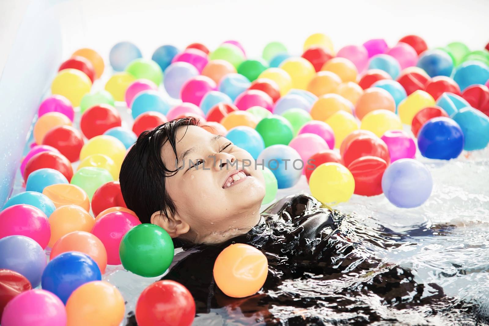 Boy playing with colourful ball in small swimming pool toy - happy boy in water pool toy concept by pairhandmade