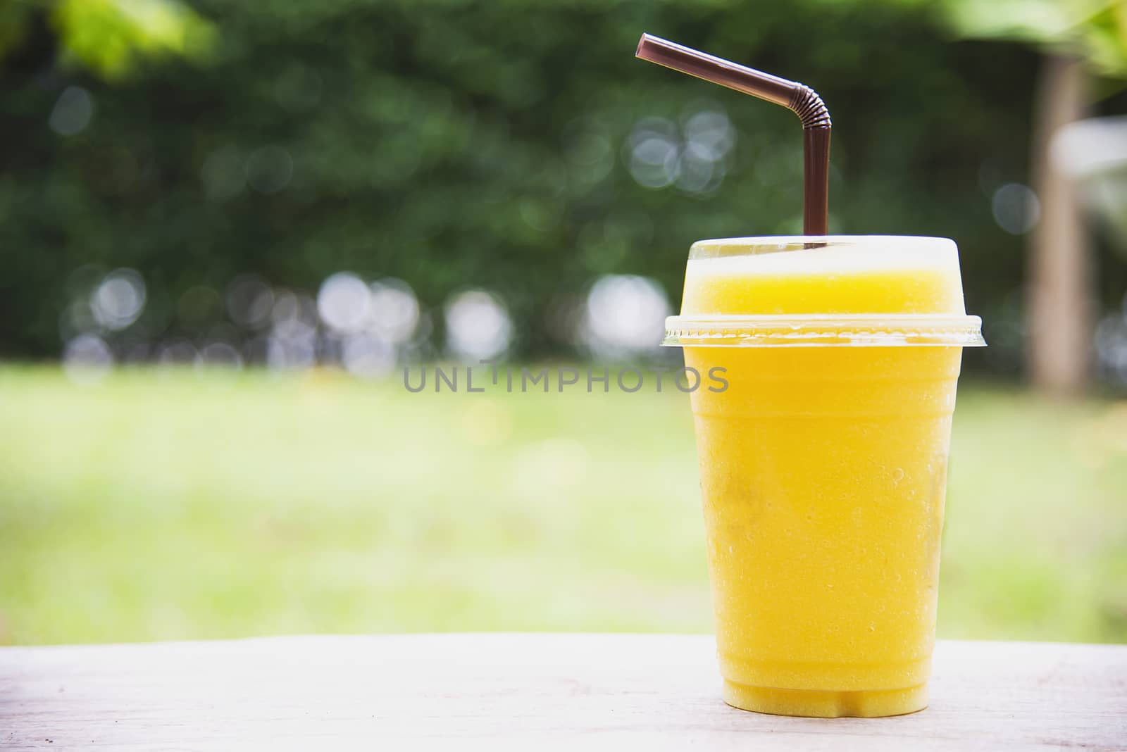 Ice mango orange blend in green garden - relax with cold fruit drink in nature concept by pairhandmade