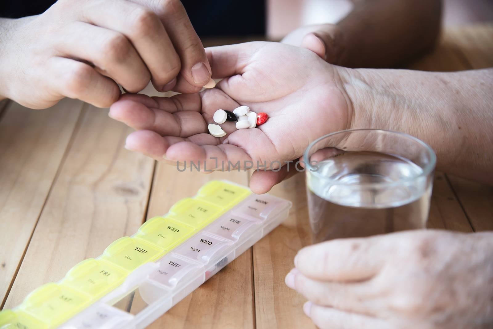 Doctor is assist patient to eat medicine tablet in pillbox correctly - people medical concept