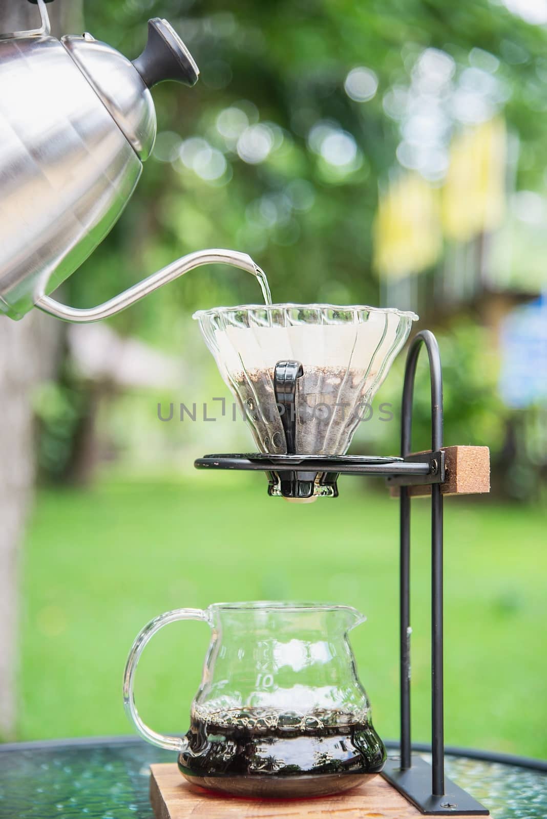 Man making drip fresh coffee in vintage coffee shop with green nature background - people with fresh coffee in nature concept