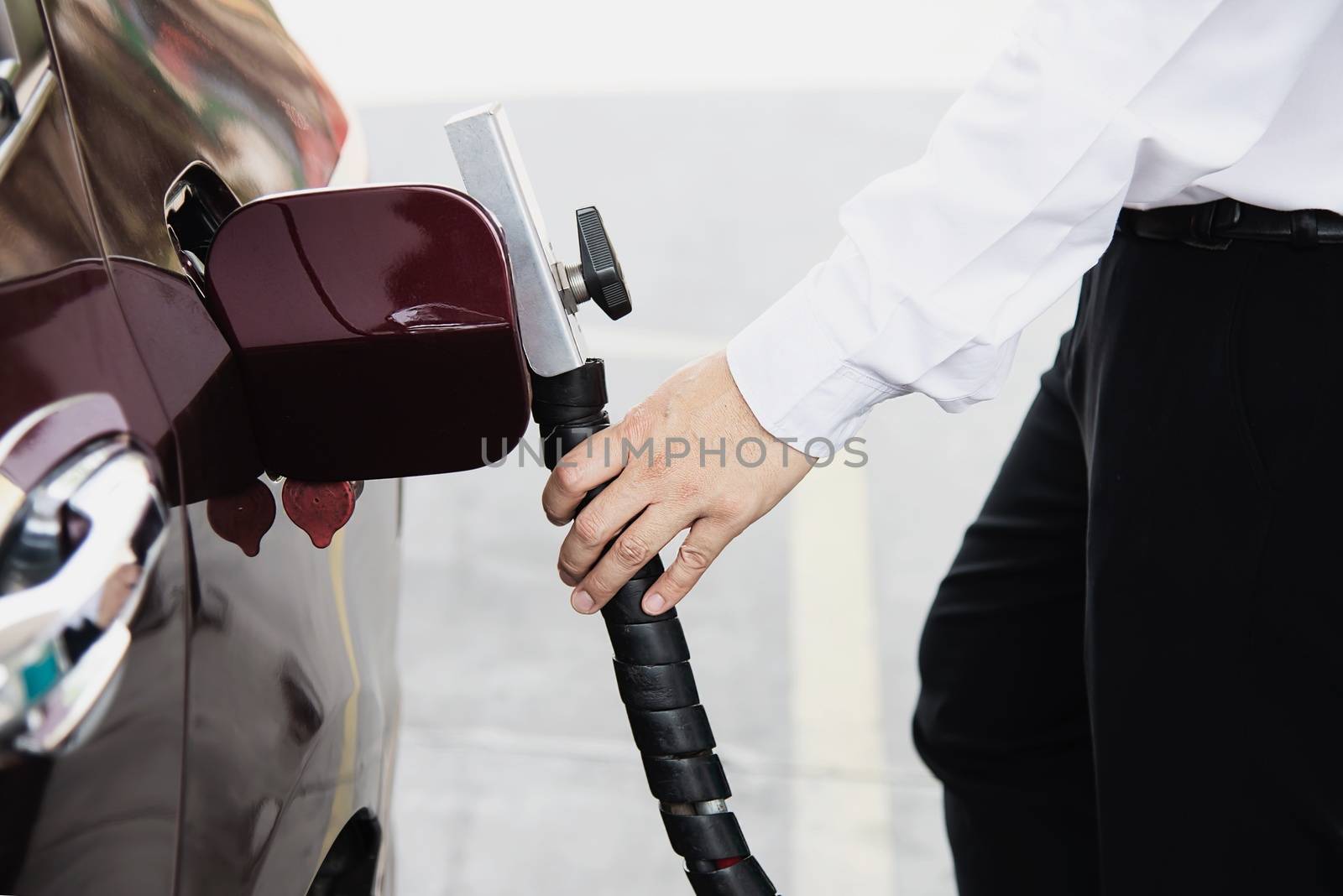 Man is putting NGV, Natural Gas Vehicle, head dispenser to a car at the gasoline station in Thailand by pairhandmade