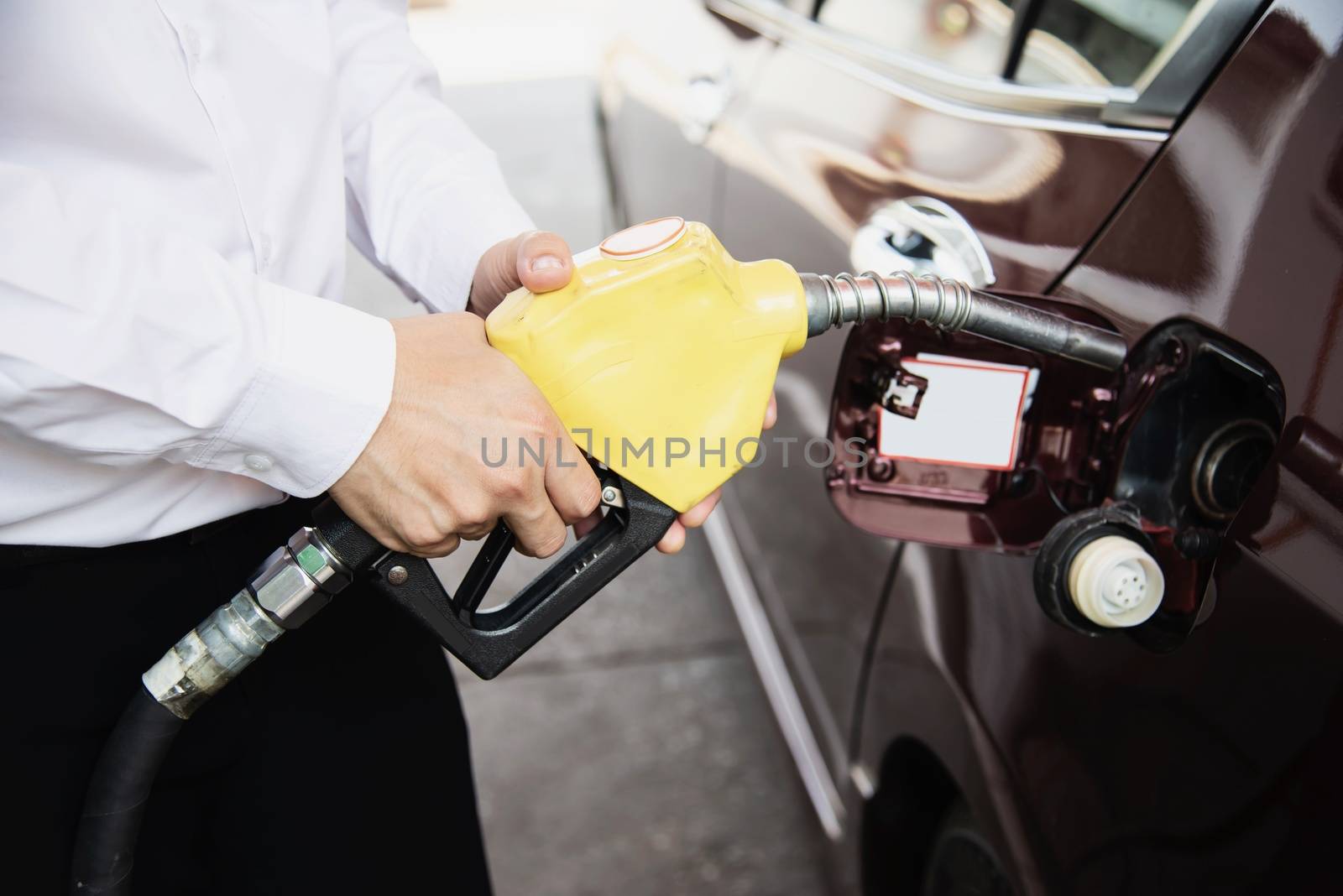 Man putting gasoline fuel into his car in a pump gas station