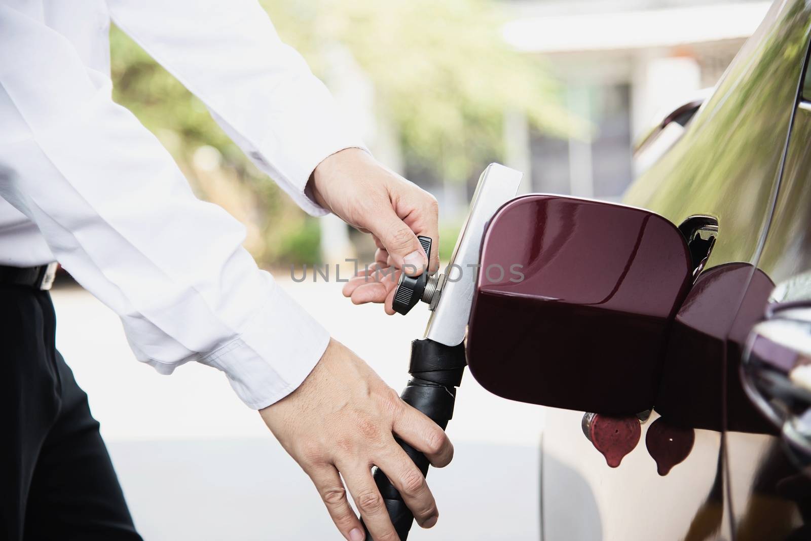 Man is putting NGV, Natural Gas Vehicle, head dispenser to a car at the gasoline station in Thailand by pairhandmade