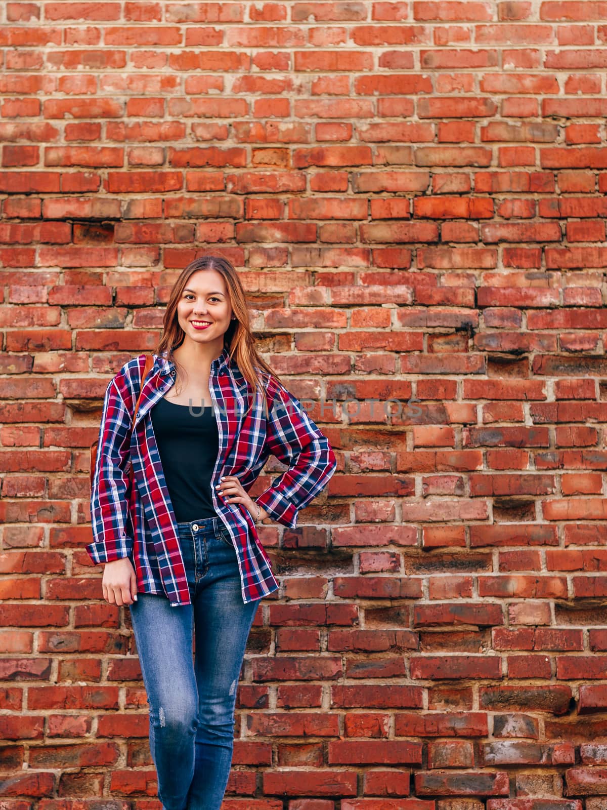 Portrait of young woman standing against brick wall by Seva_blsv