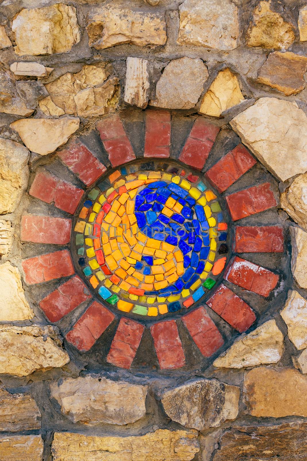 Circular mosaic religious symbol of Yin and yang on stone wall.