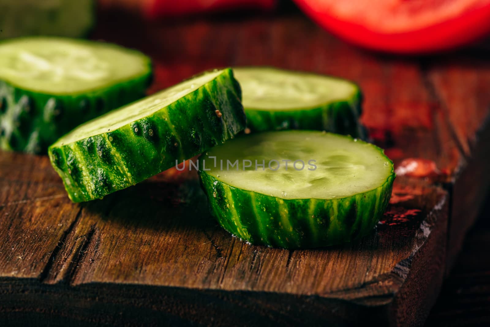 Sliced vegetables. Tomatoes, cucumbers and chili peppers over wooden background.