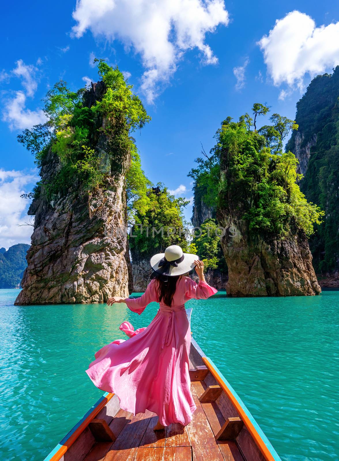 Beautiful girl standing on the boat and looking to mountains in Ratchaprapha Dam at Khao Sok National Park, Surat Thani Province, Thailand. by gutarphotoghaphy
