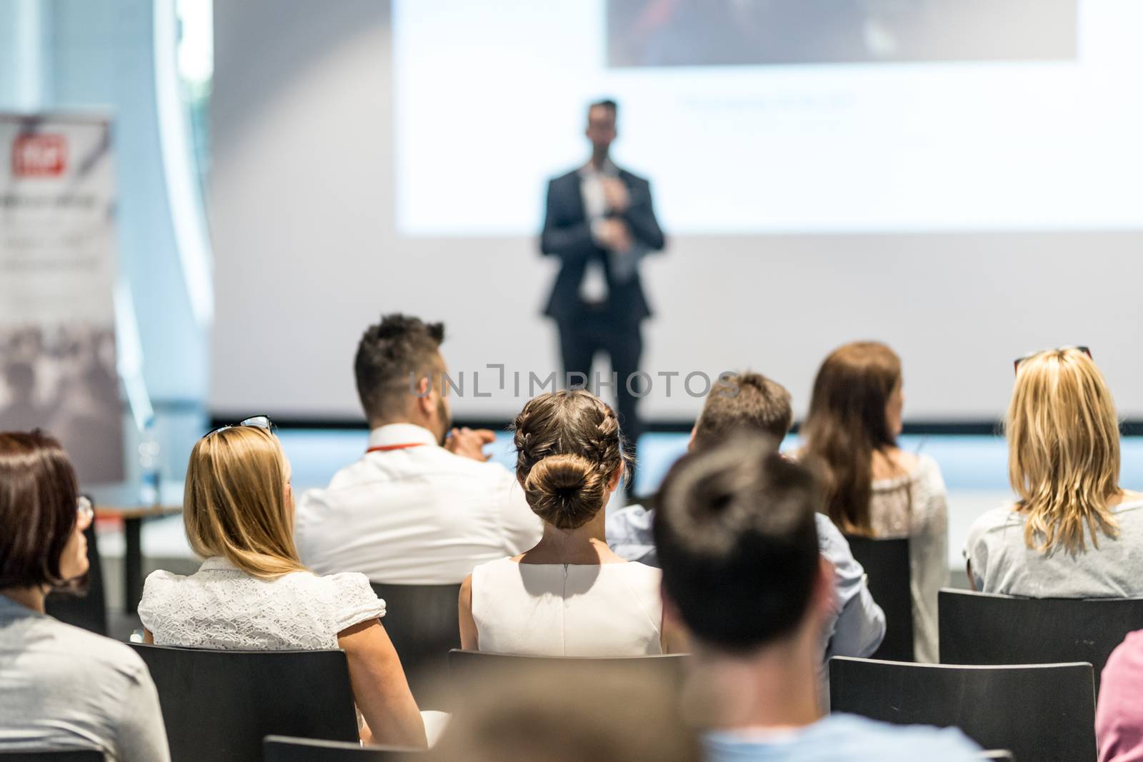 Male speaker giving a talk in conference hall at business event. Audience at the conference hall. Business and Entrepreneurship concept. Focus on unrecognizable people in audience.