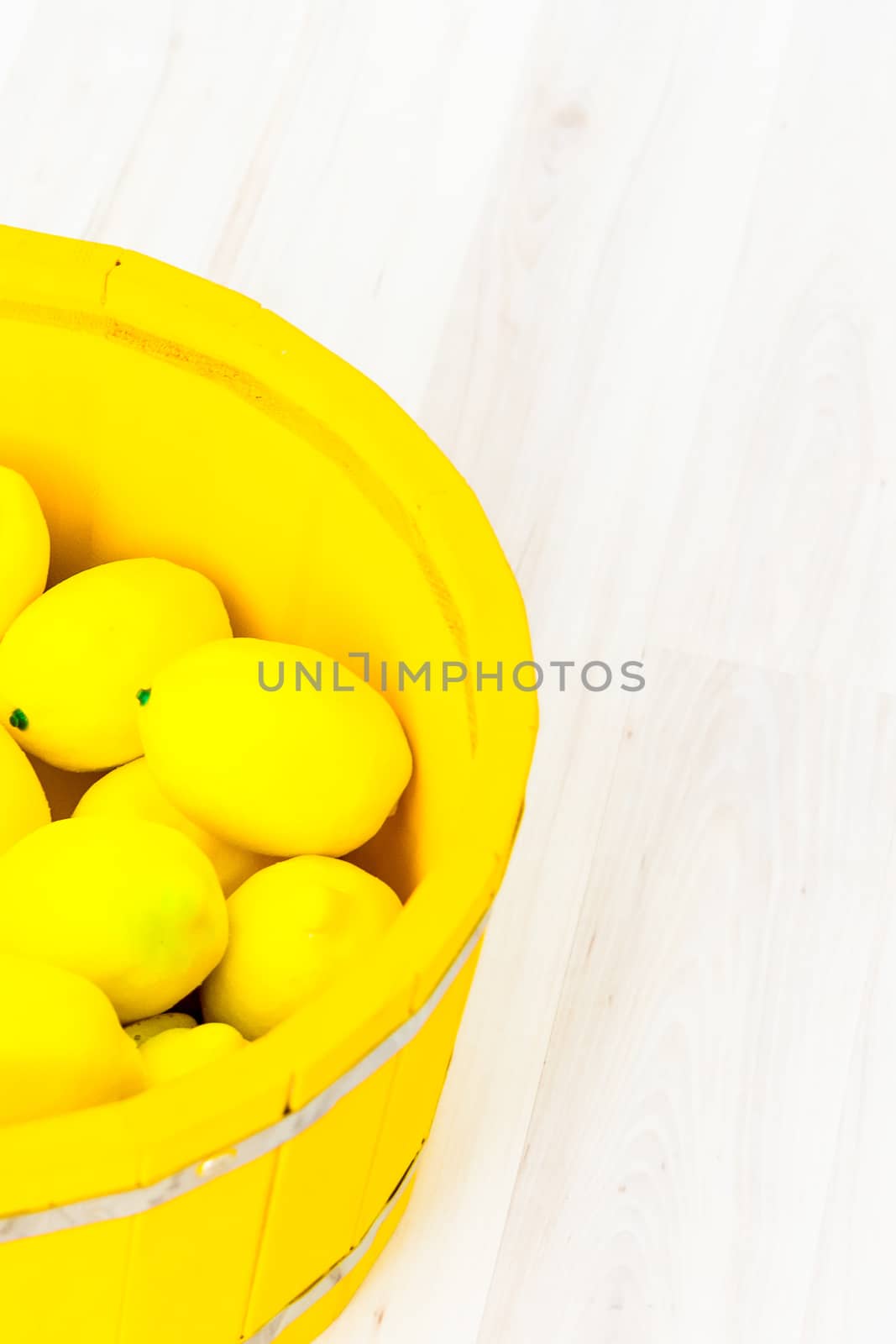 large yellow lemons in a large yellow wooden basin standing on the floor