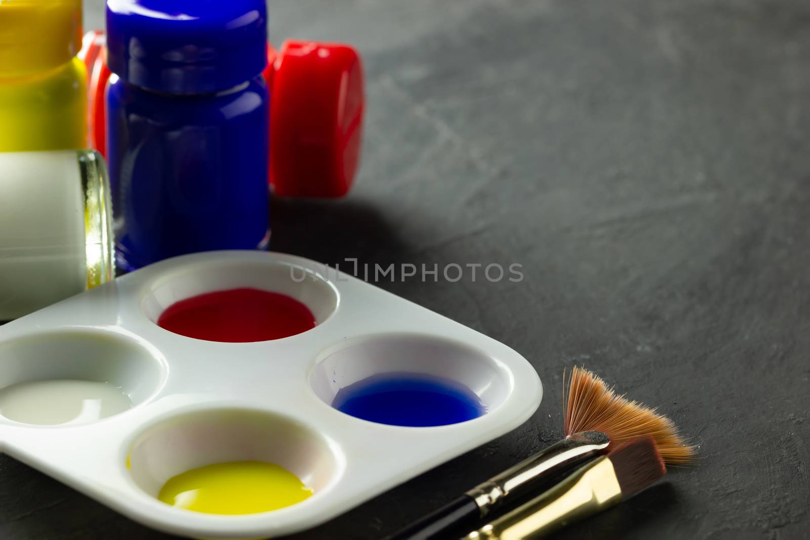 Color palette and artist paint brush with poster color bottle on black cement floor. Copy space for text. Concept of art education.