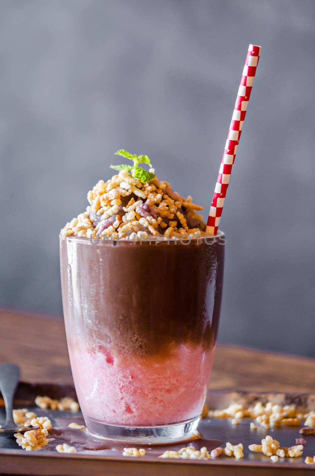 Chocolate and strawberry smoothie with rice krispie treats topping on table in resturant bar.