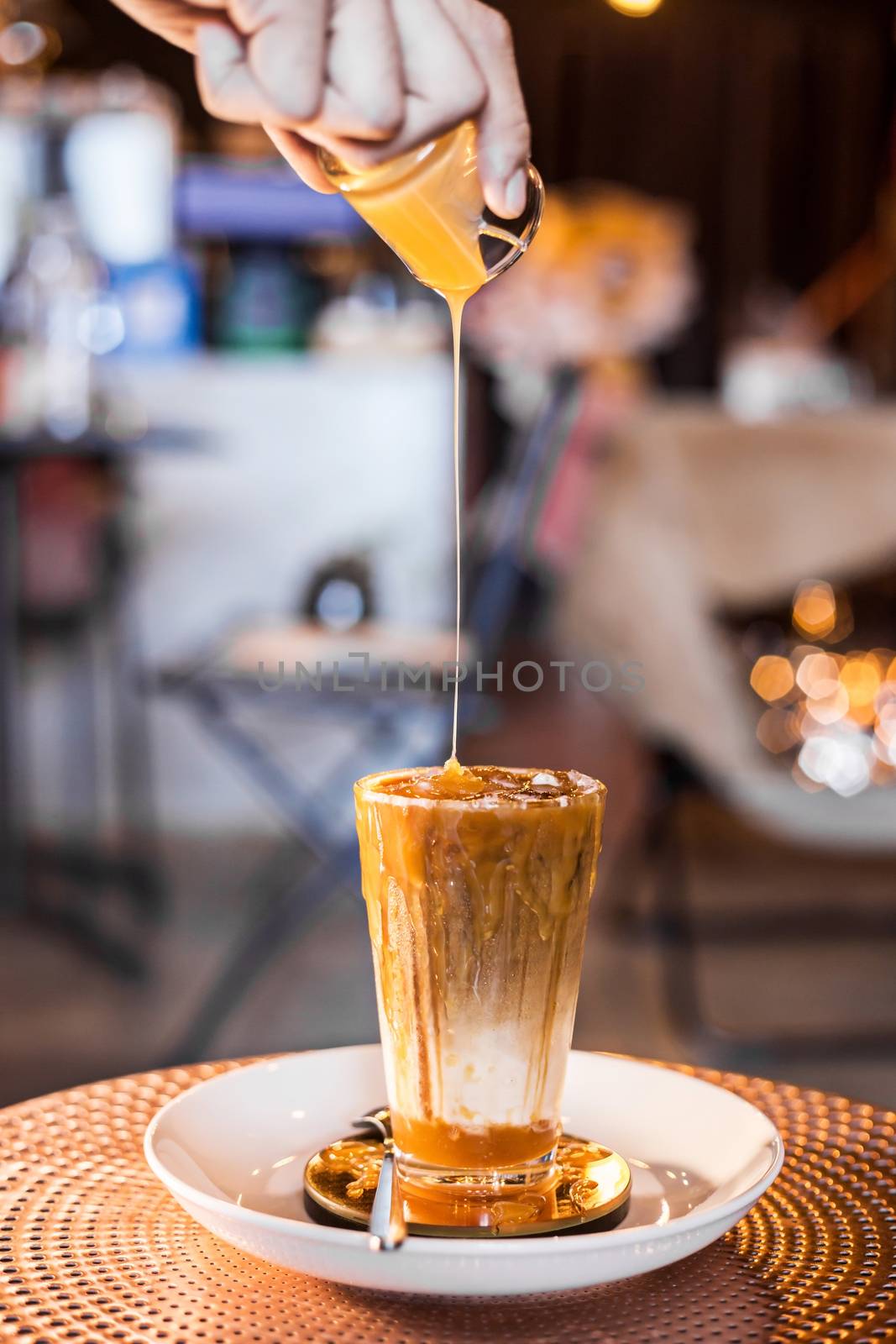 Iced coffee with milk in tall glasses on the table with caramel syrup poured on top.