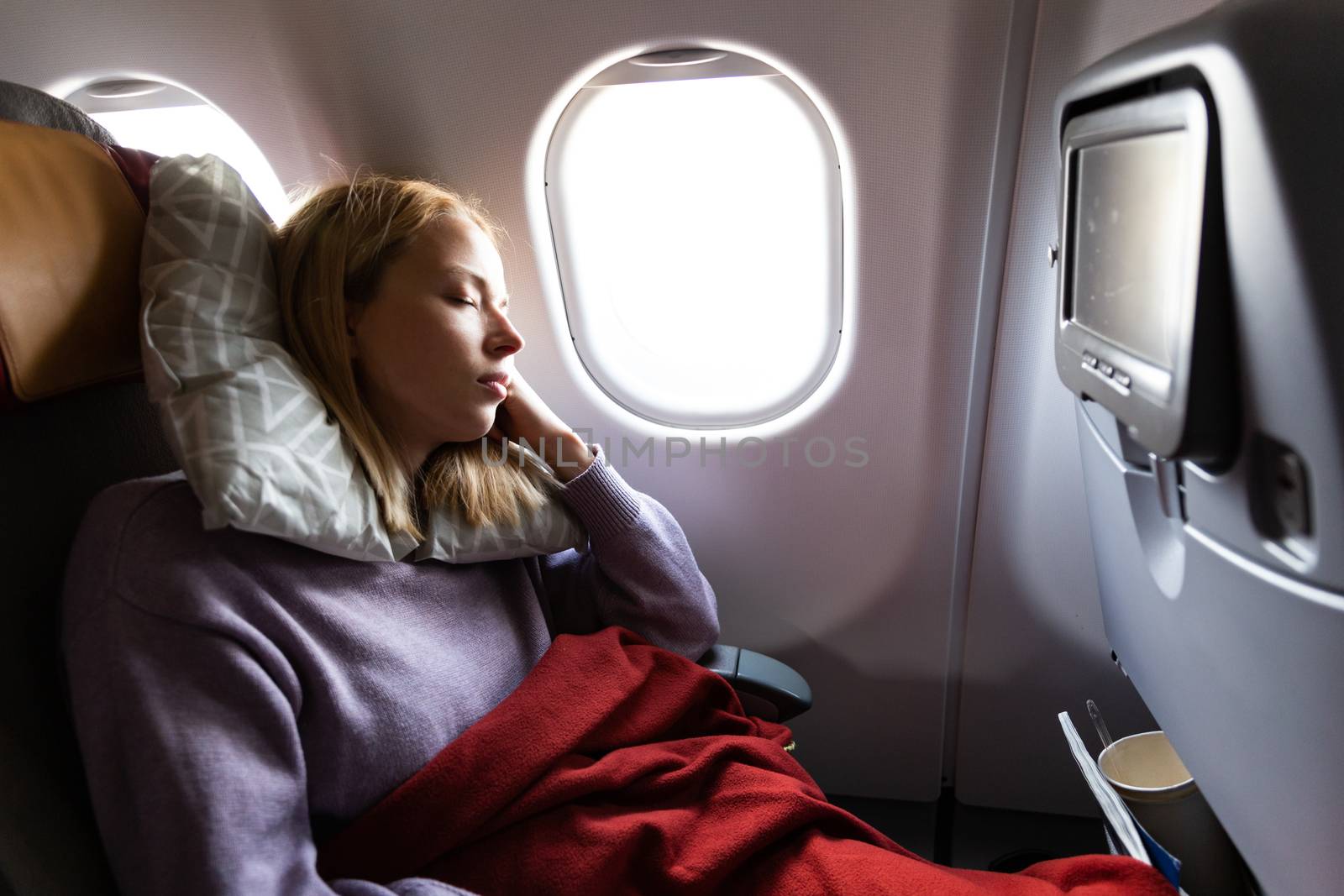 Tired blonde casual caucasian lady sleepin on seat while traveling by airplane. Commercial transportation by planes. by kasto