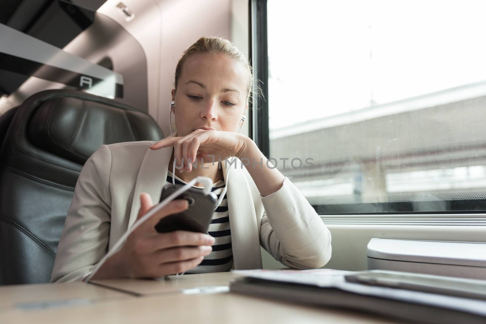 Businesswoman communicating on mobile phone while traveling by train. by kasto