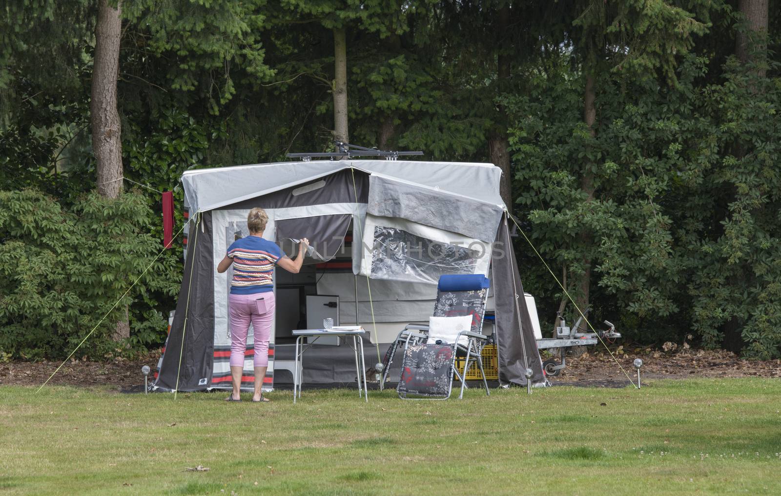 woman busy with installing a roof trailer or folding caravan on a camping in the forest