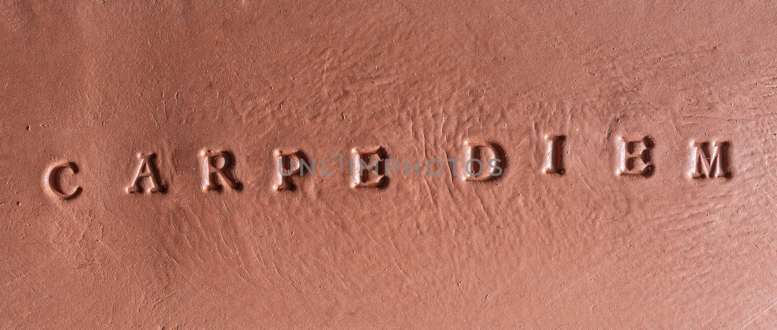  the phrase  “Carpe diem” written in Latin on a terracotta tablet
