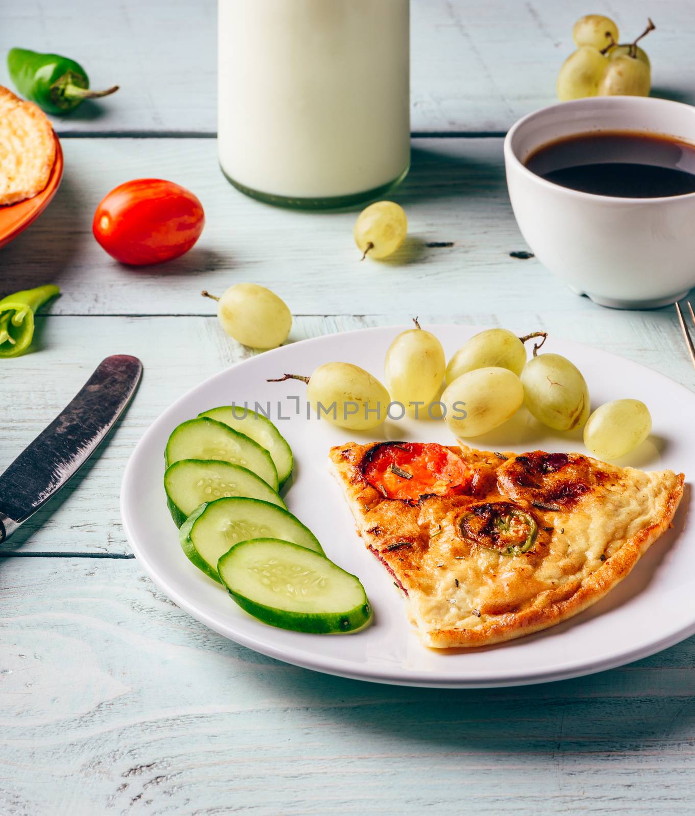 Healthy breakfast with frittata, fruits, vegetables, milk and cup of coffee on light wooden background.