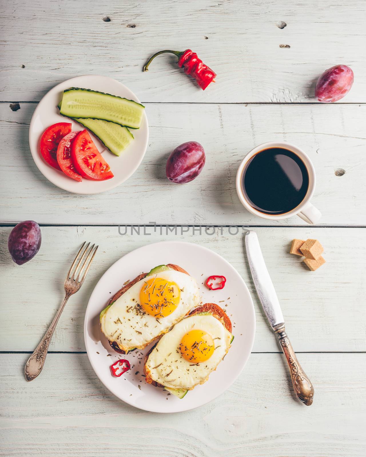 Breakfast toasts with vegetables and fried egg on white plate, cup of coffee and some fruits over wooden background. Clean eating food concept. View from above.