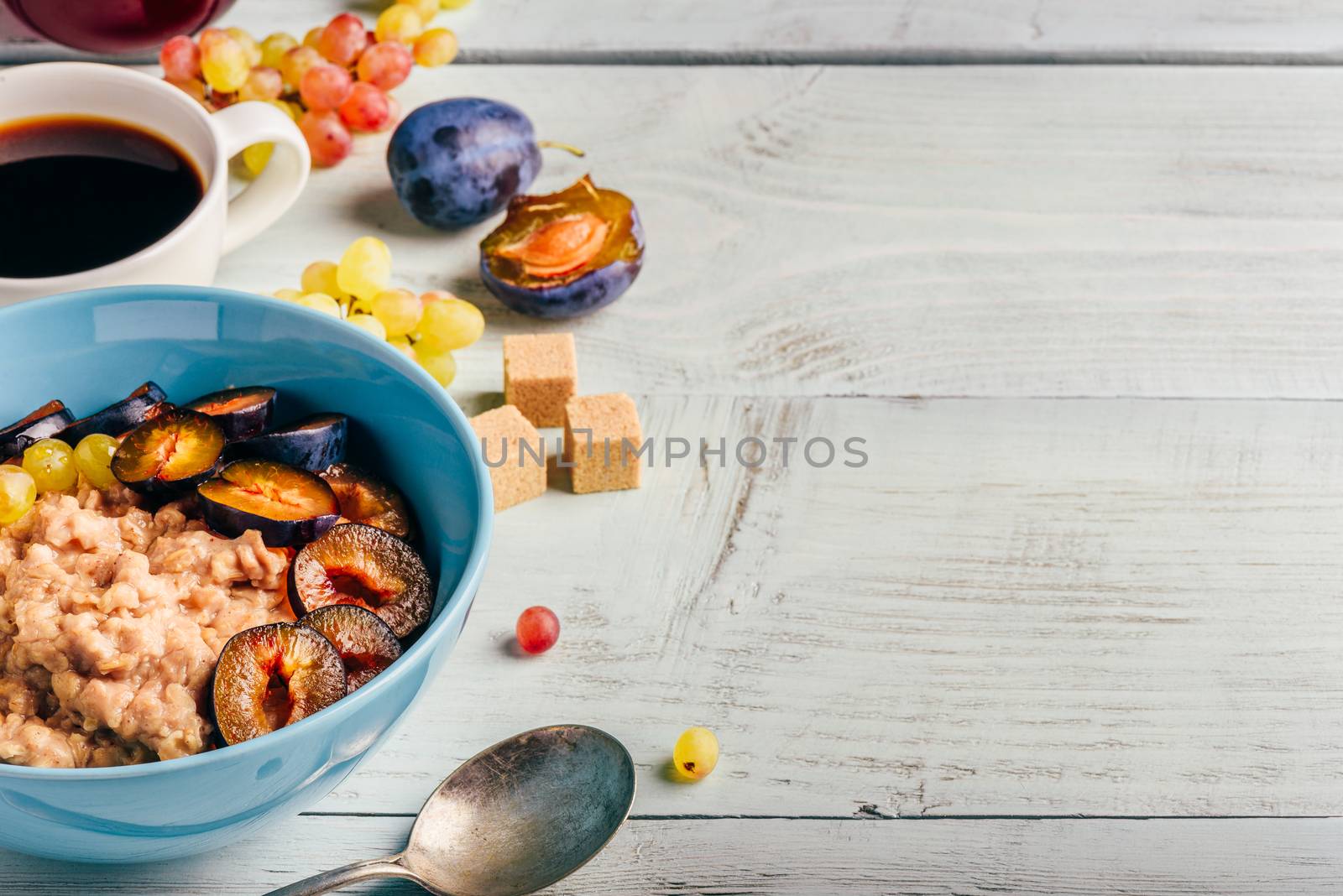 Healthy breakfast concept. Porridge with fresh plum, green grapes and cup of coffee.