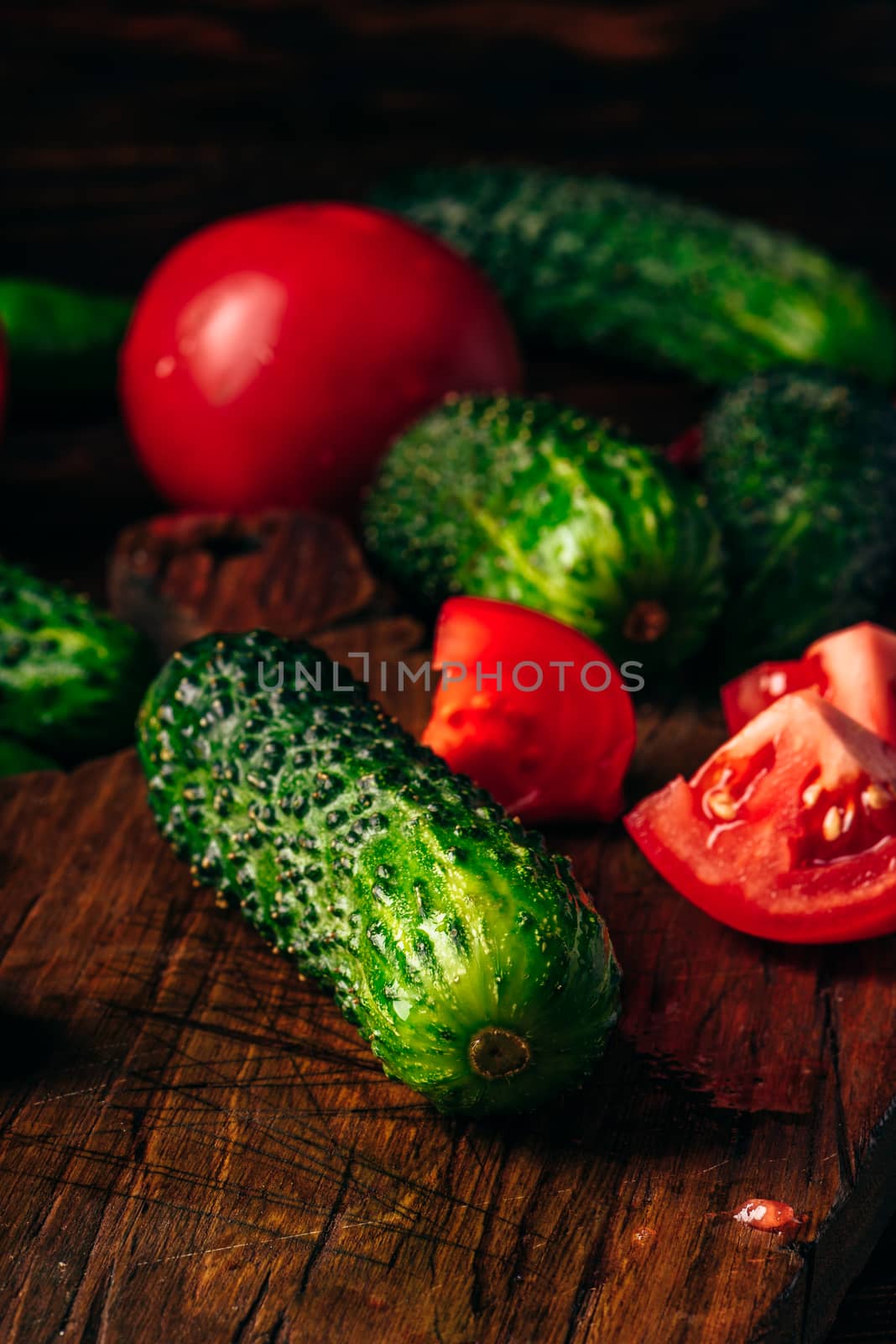 Fresh cucumbers, tomatoes and chili peppers on cutting board for preparing salad.