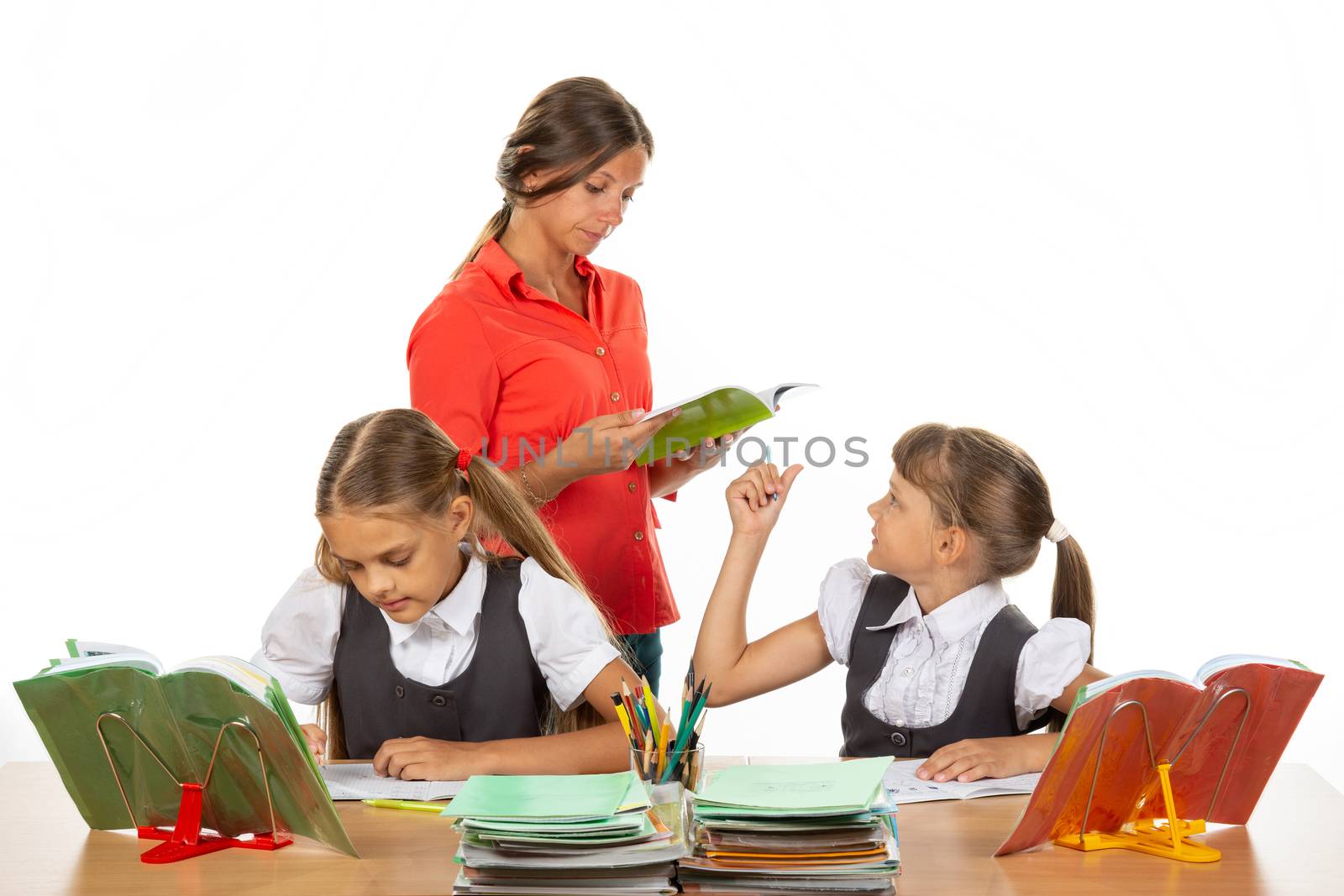 The teacher helps the schoolgirl to understand the task
