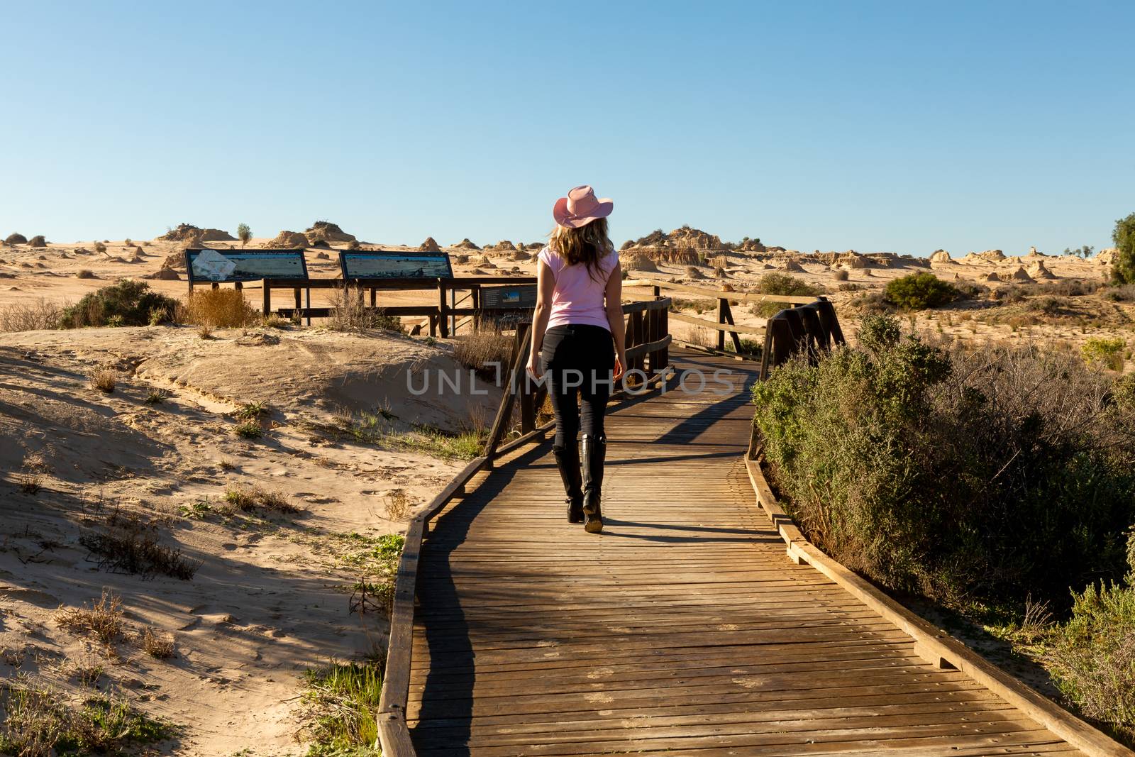 Tourist visitor walks along the timber boardwalk  to the desert and Mungo National Park viewing platforms