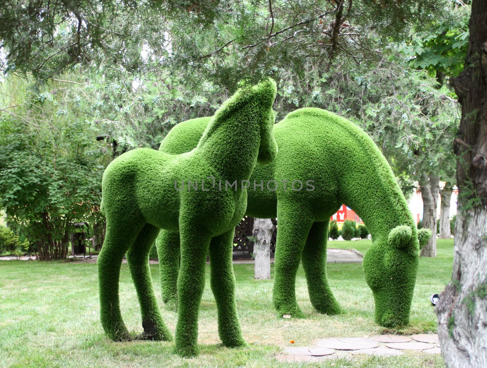 Sculpture of horses made of artificial grass on a tree background. by Igor2006