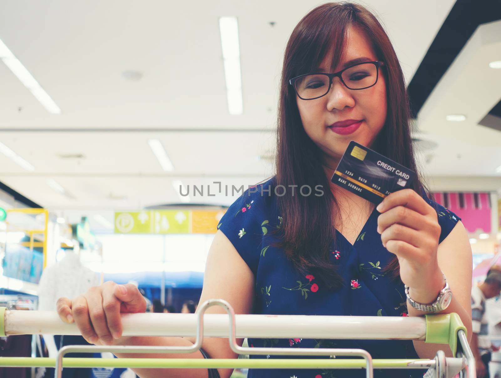 Women holding credit cards and shopping cart by anankkml