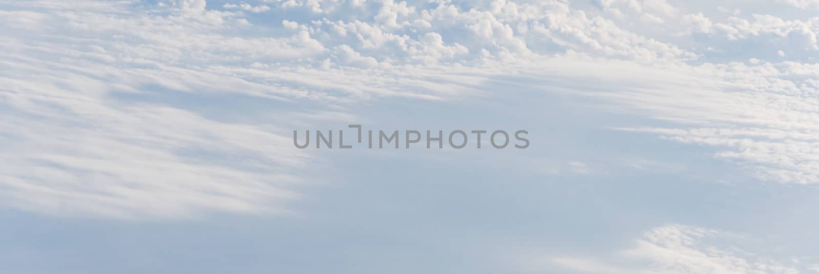 Panorama beautiful and unusual Altocumulus or Cirrocumulus cloud formation seen from airplane window at sunrise. Skyline view above the clouds from the air