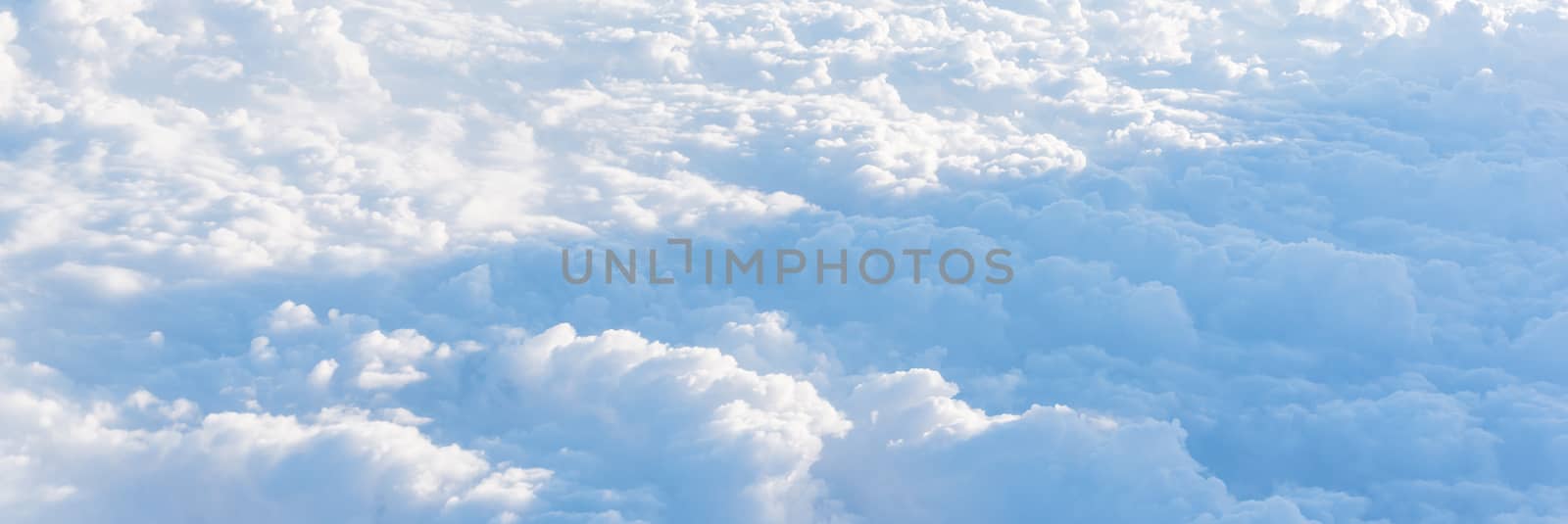 Panorama beautiful and unusual Altocumulus or Cirrocumulus cloud formation seen from airplane window at sunrise. Skyline view above the clouds from the air