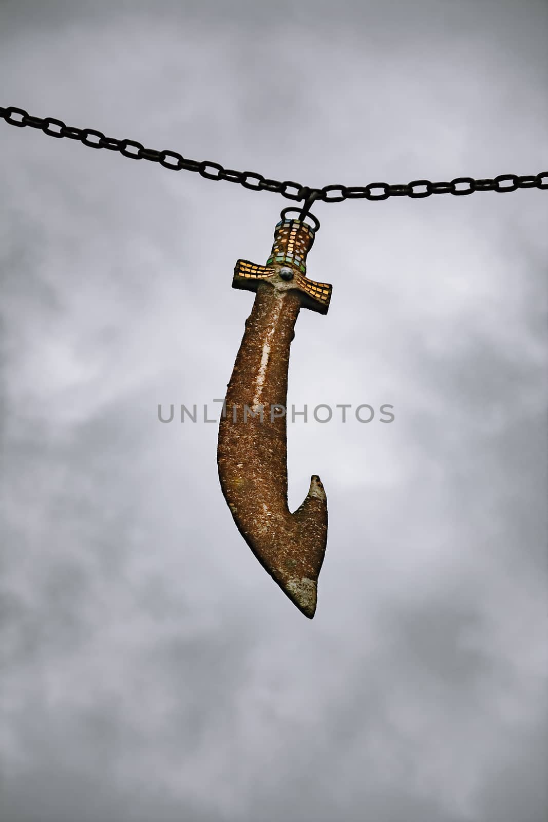 Old rusty sword hanging on a chain