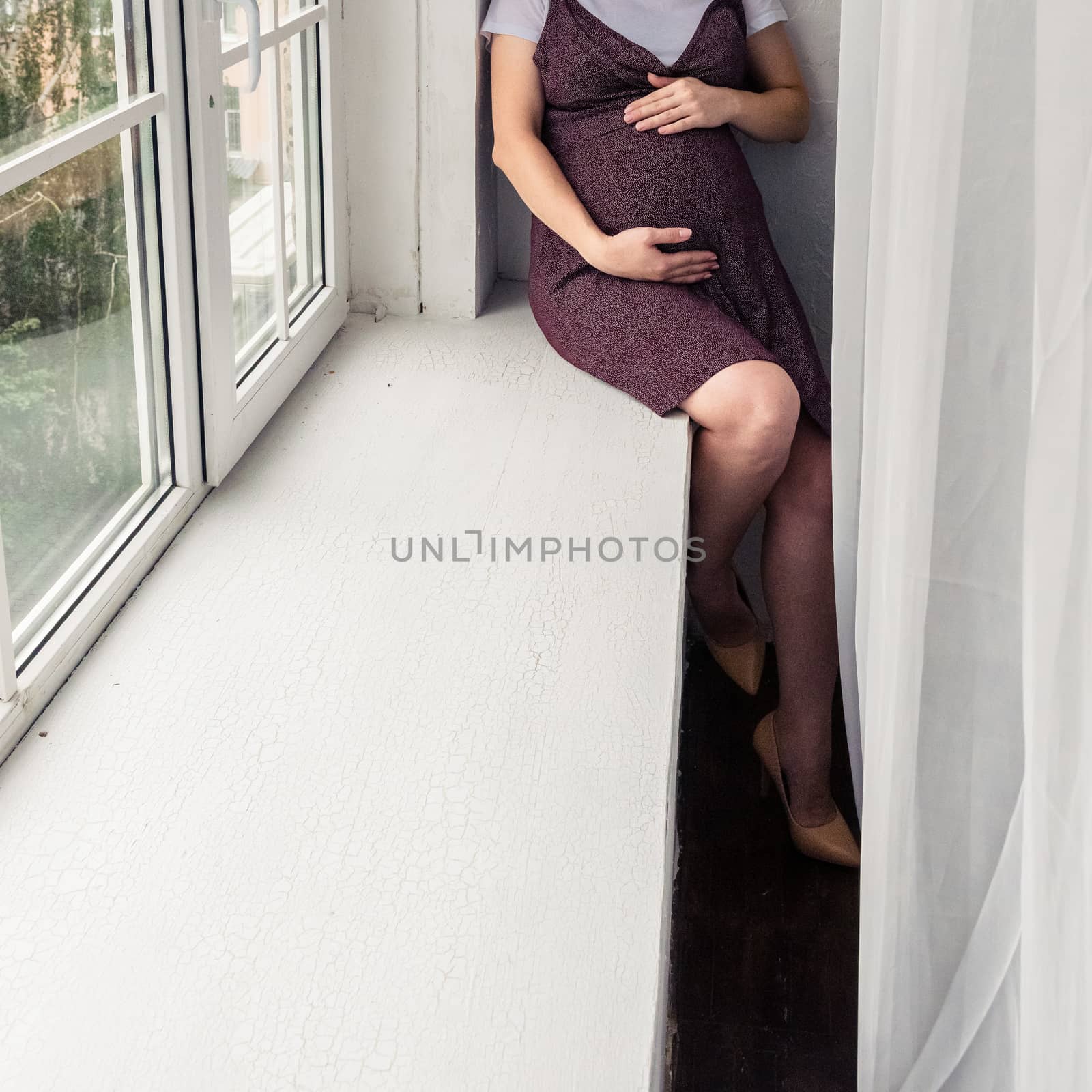pregnant woman in a dark dress in the interior of a light room by alexandr_sorokin