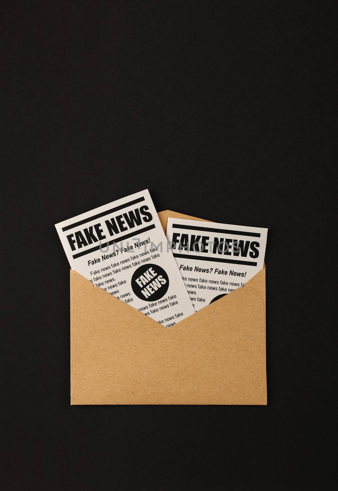 Envelope with FAKE NEWS newspapers over black by BreakingTheWalls
