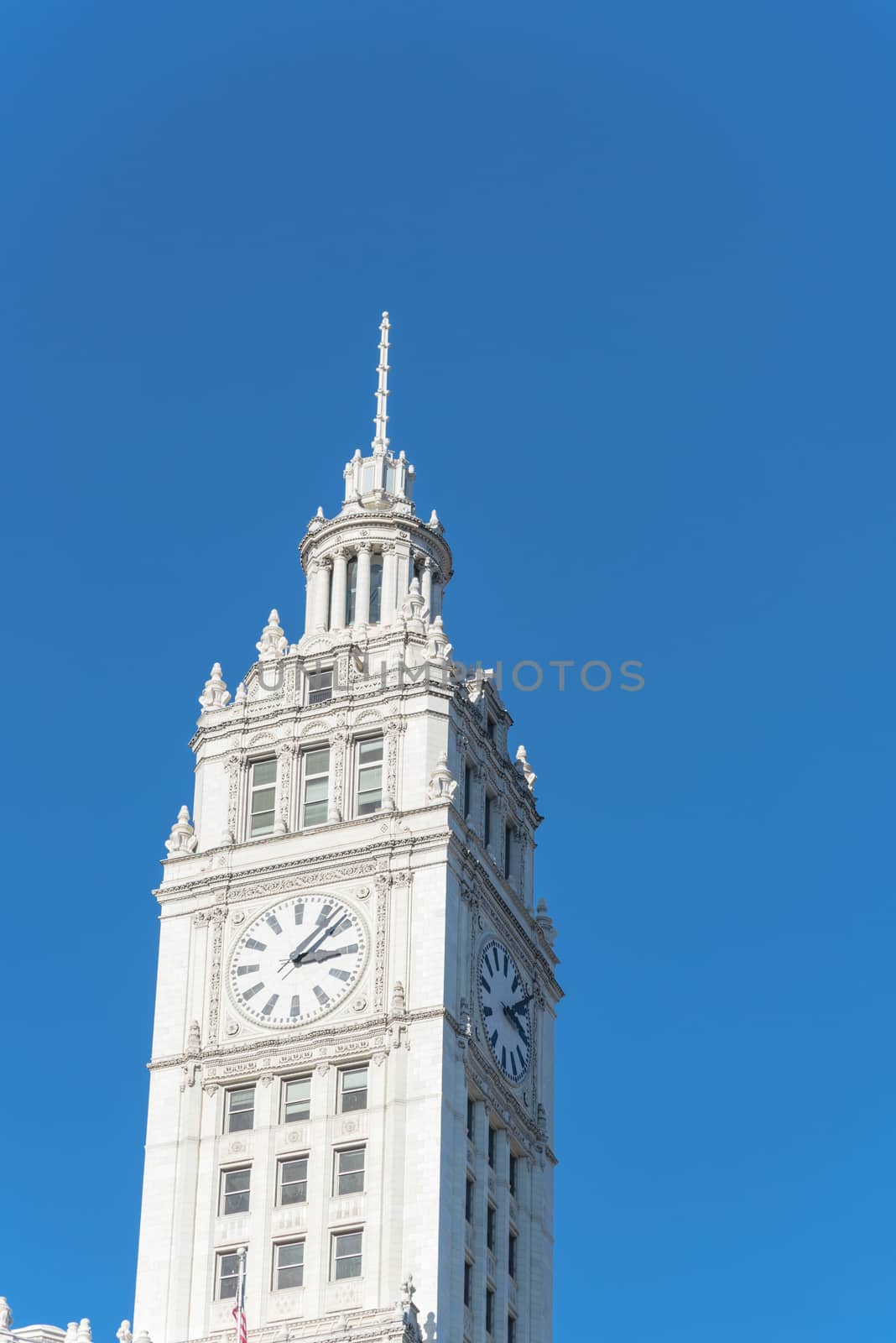 Low angle view top of traditional building with a clock faces pointing in all directions. Clock tower along Michigan Avenue in downtown Chicago, Illinois.