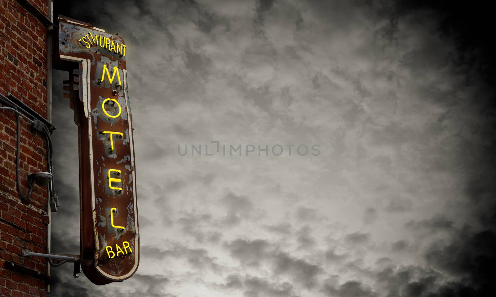 A Grungy Old Neon Motel Sign Against A Stormy Sky With Copy Space