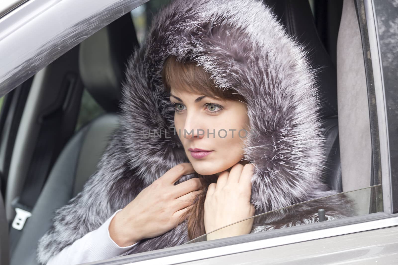 The expressive face of a young pretty girl in the window of the car