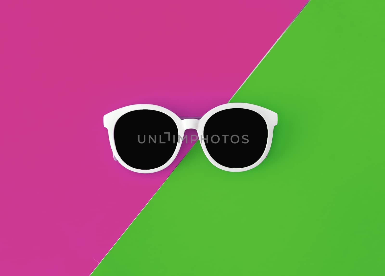 Sunny stylish white sunglasses on a bright green-cyan and crimson-pink background, top view, isolated. Copy space. Flat lay by Tanacha